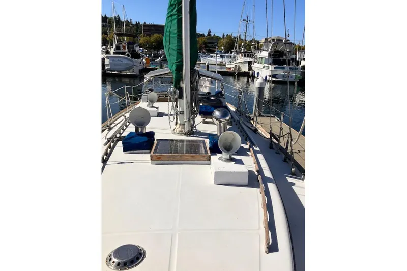 Slide: The Image of 1981 Valiant Cutter sailboat docked in a marina, featuring a clean deck and green sail. - 16