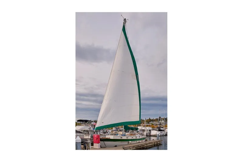 Slide: The Image of 1981 Valiant Cutter sailboat docked with green-trimmed sail raised. - 2