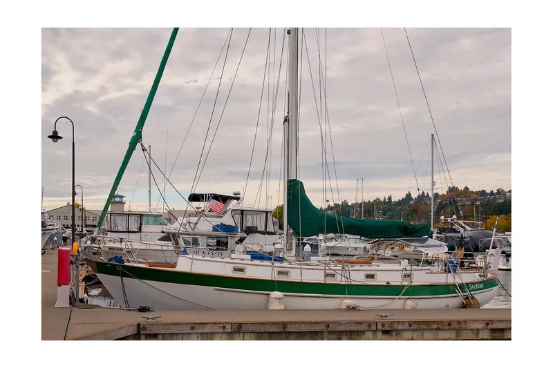 Slide: The Image of 1981 Valiant Cutter sailboat docked at a marina under cloudy skies. - 44