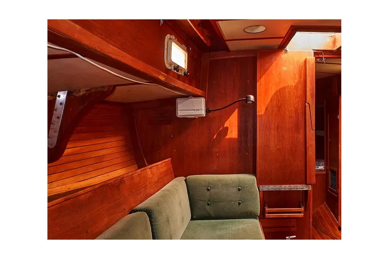 Slide: The Image of Interior of 1981 Valiant Cutter sailboat with wooden paneling and green cushioned seating. - 45