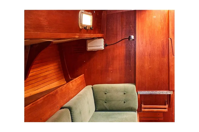 Slide: The Image of Interior of 1981 Valiant Cutter sailboat with wooden paneling and green cushioned seating. - 53