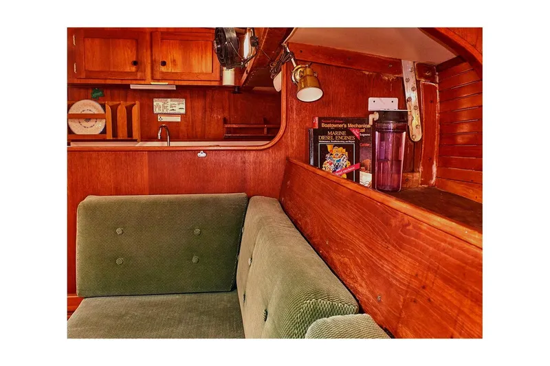 Slide: The Image of 1981 Valiant Cutter interior with green sofa, wooden cabinetry, and marine engine book. - 56