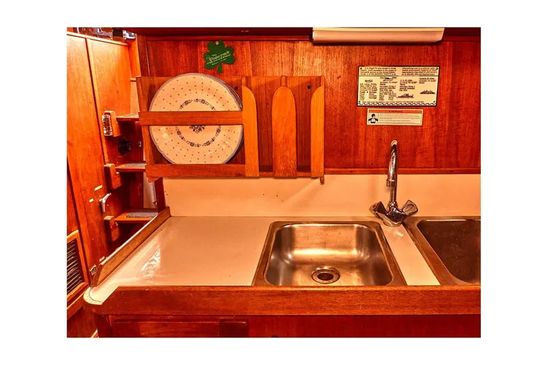 Slide: The Image of 1981 Valiant Cutter kitchen with wooden cabinetry, stainless steel sink, and plate rack. - 60
