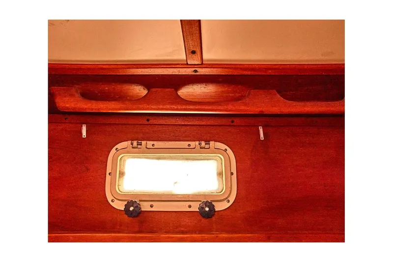 Slide: The Image of Interior view of 1981 Valiant Cutter boat, featuring wooden paneling and a porthole window. - 70