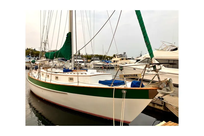 Slide: The Image of 1981 Valiant Cutter sailboat docked at marina, featuring green accents and white hull. - 8
