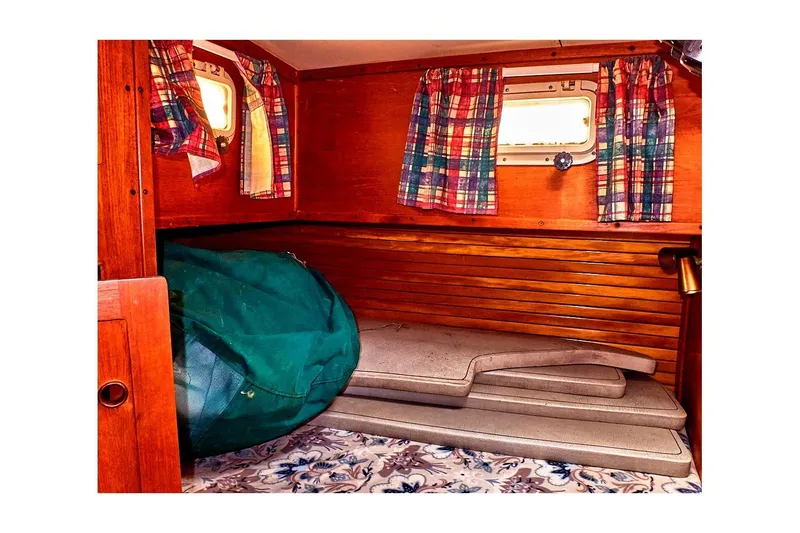 Slide: The Image of Cozy 1981 Valiant Cutter cabin interior with plaid curtains and wooden paneling. - 81