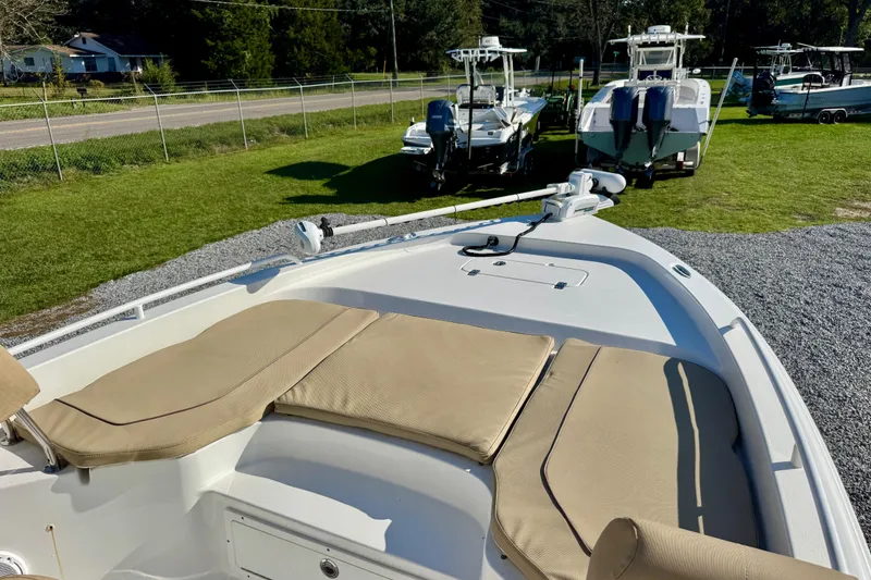Slide: The Image of 2018 Sea Hunt BX 25 FS boat with cushioned seating, parked on gravel near other boats. - 5