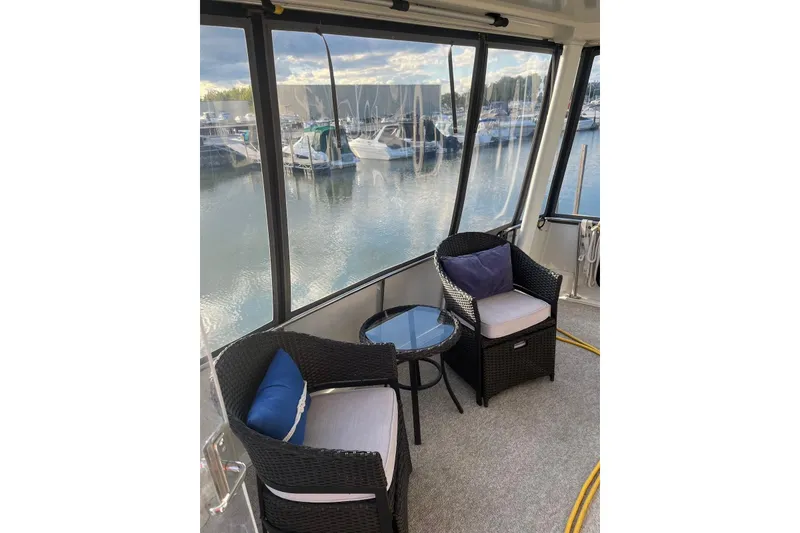 Slide: The Image of 1993 Carver 350 Aft Cabin Motor Yacht interior with wicker chairs and marina view. - 4