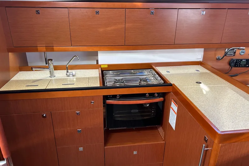 Slide: The Image of 2014 Beneteau Oceanis 41 yacht kitchen with wood cabinetry, sink, and stove. - 18