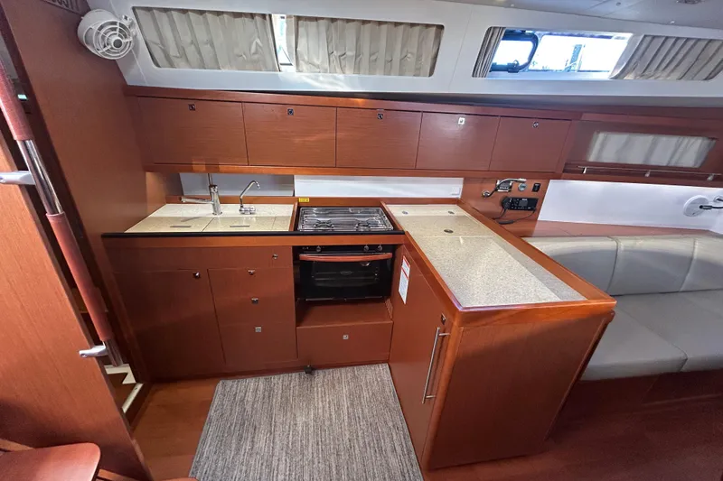 Slide: The Image of 2014 Beneteau Oceanis 41 yacht interior kitchen with wood cabinetry and modern appliances. - 19