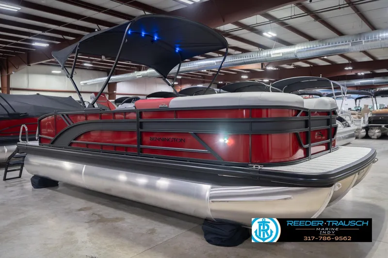 Slide: The Image of 2026 Bennington 22 SLJ pontoon boat in showroom, featuring sleek red design and canopy. - 6