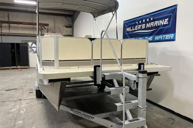 Slide: The Image of 2022 Fiesta 16 Fish N Fun pontoon boat on trailer in indoor showroom. - 2