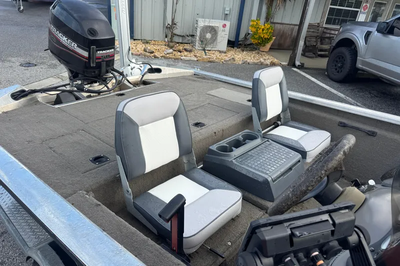 Slide: The Image of 2020 Tracker boat interior with dual seats and motor, parked outdoors. - 12