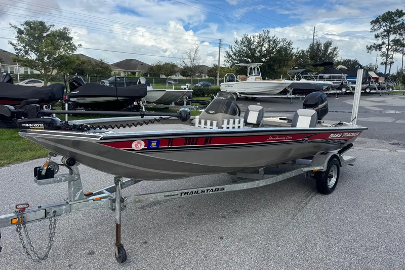 Slide: The Image of 2020 Tracker Bass boat on trailer, parked in a marina with other boats. - 2