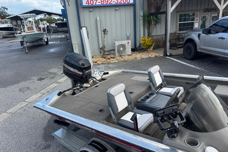 Slide: The Image of 2020 Tracker boat with motor, parked near a building and vehicles. - 11