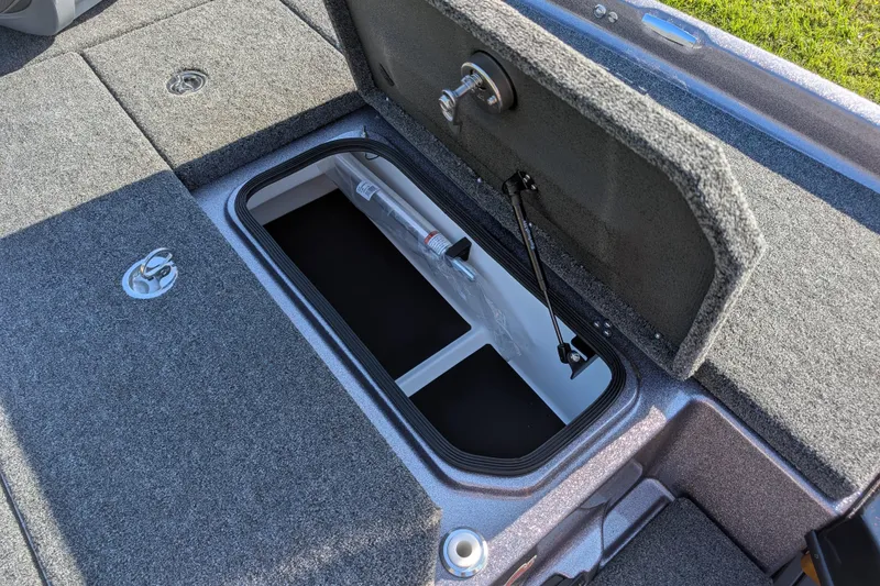 Slide: The Image of Open storage compartment on 2026 Bass Cat Eyra SP boat, featuring carpeted interior. - 16