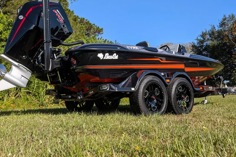 Slide: The Image of 2026 Bass Cat Eyra SP boat on trailer, black with orange accents, parked on grass. - 5