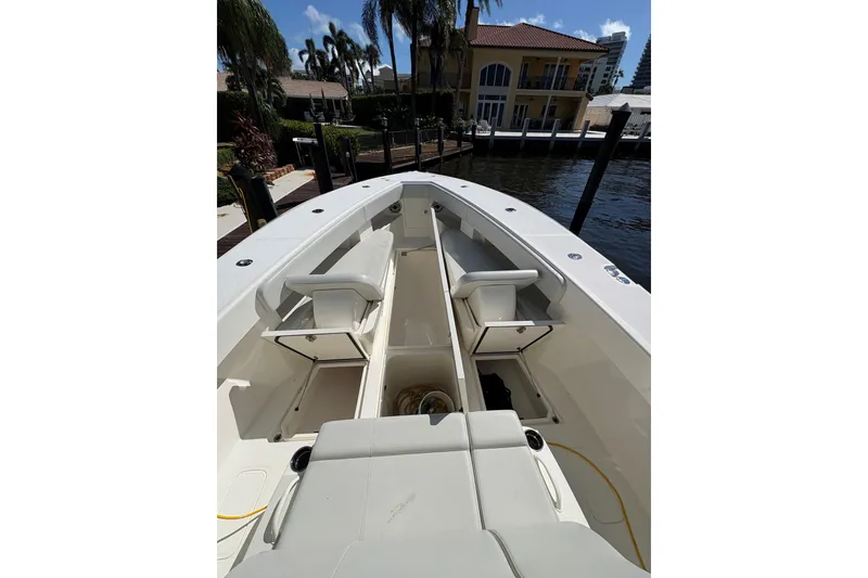 Slide: The Image of 2019 SeaVee 370z boat interior with seating and storage, docked near waterfront homes. - 12