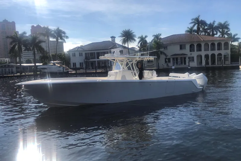 Slide: The Image of 2019 SeaVee 370z boat on water, with waterfront homes and palm trees in the background. - 2