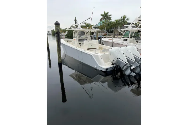 Slide: The Image of 2019 SeaVee 370z boat docked with triple outboard engines, calm water reflection. - 4