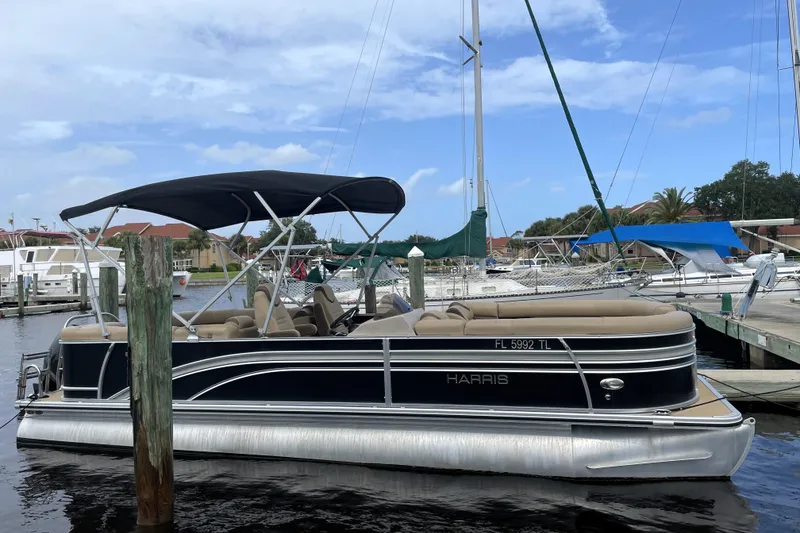 The Image of 2019 Harris Sunliner 250 pontoon boat docked at marina with blue sky background. - 0