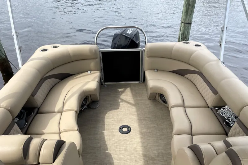 Slide: The Image of 2019 Harris Sunliner 250 pontoon boat with beige seating and water backdrop. - 18