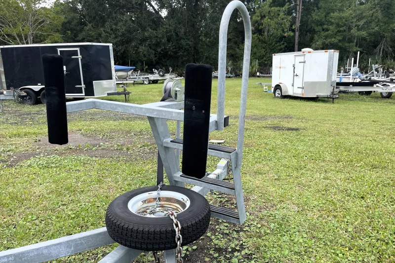 Slide: The Image of Boat trailer with spare tire on grassy lot, surrounded by utility trailers. - 30