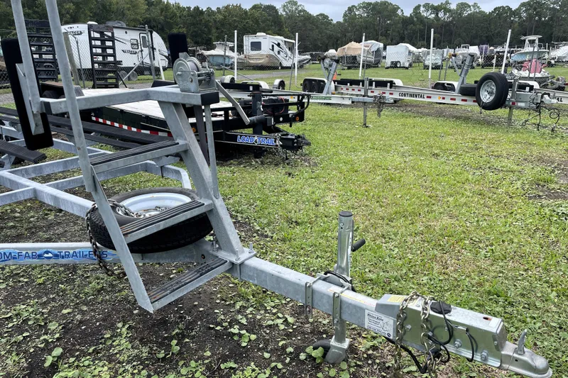 Slide: The Image of Trailer lot with various trailers, including a 2019 Harris Sunliner 250, on grassy field. - 41