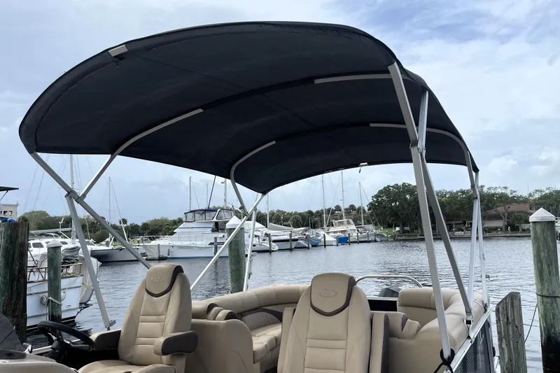 Slide: The Image of 2019 Harris Sunliner 250 pontoon boat with canopy, docked at marina. - 6