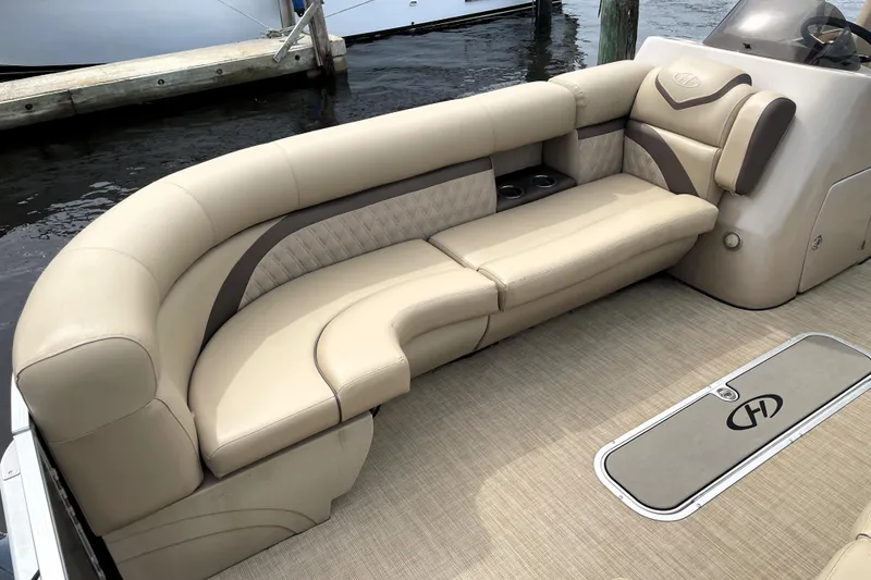 Slide: The Image of Luxurious seating on 2019 Harris Sunliner 250 pontoon boat, featuring beige upholstery and cup holders. - 8
