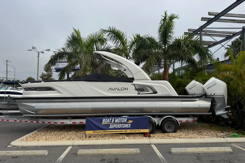 The Image of 2026 Avalon Excalibur 27' boat displayed at dealership with palm trees in background. - 1