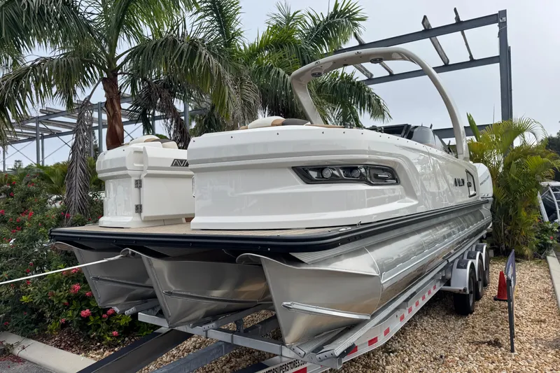 Slide: The Image of 2026 Avalon Excalibur 27' boat on trailer, surrounded by tropical plants. - 10