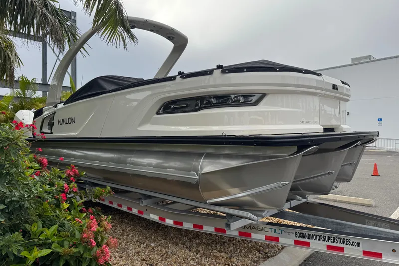 Slide: The Image of 2026 Avalon Excalibur 27' boat on trailer, surrounded by tropical plants. - 6