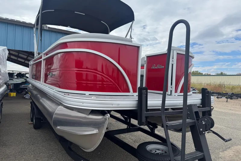 Slide: The Image of 2026 Sun Tracker Party Barge 22 RF DLX pontoon boat with red exterior, docked outdoors. - 3
