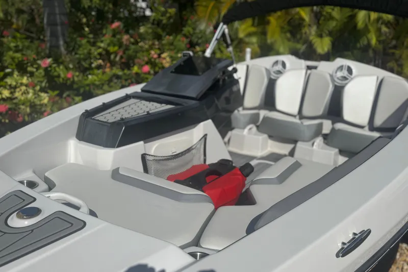 Slide: The Image of 2018 Scarab 165 G boat interior with seating and dashboard, surrounded by lush greenery. - 3