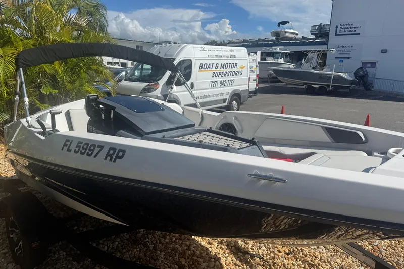 Slide: The Image of 2018 Scarab 165 G boat displayed outdoors at a dealership with service vehicles nearby. - 6