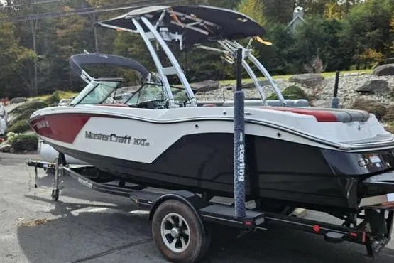 Slide: The Image of 2017 MasterCraft NXT20 boat on trailer, parked outdoors with trees in background. - 3
