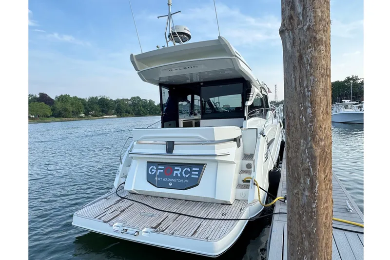 Slide: The Image of 2024 Galeon 425 HTS yacht docked at marina, rear view with water and trees. - 2