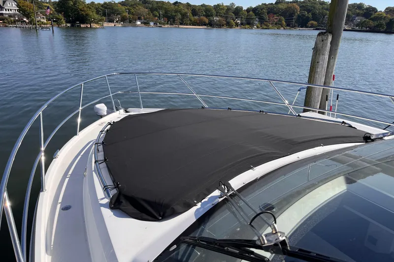 Slide: The Image of 2024 Galeon 425 HTS yacht bow with black cover, docked by serene waters. - 31