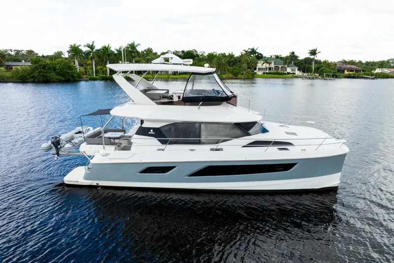 Slide: The Image of 2019 Aquila 44 Yacht on calm water, featuring a small dinghy at the stern. - 55