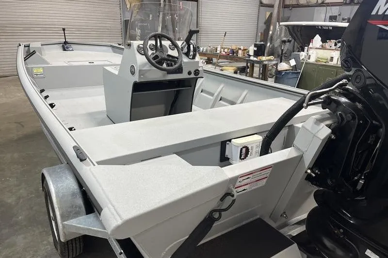 Slide: The Image of 2025 SeaArk 1860 MVJT boat in a garage, featuring steering console and outboard motor. - 5