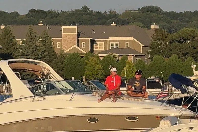 Slide: The Image of Two people relaxing on a 2006 Larson Cabrio 274 boat at a marina. - 10