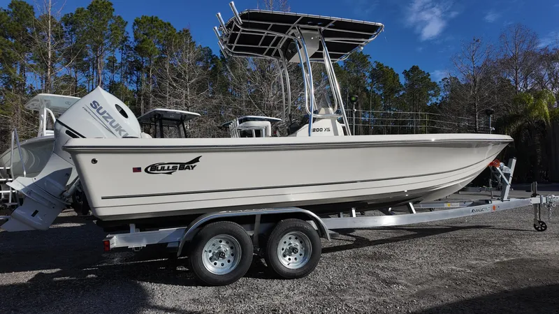 Slide: The Image of 2025 Bulls Bay 2200XS boat on trailer with Suzuki engine, parked outdoors. - 1