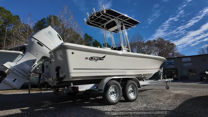 Slide: The Image of 2025 Bulls Bay 2200XS boat on trailer, parked outdoors under clear blue sky. - 2