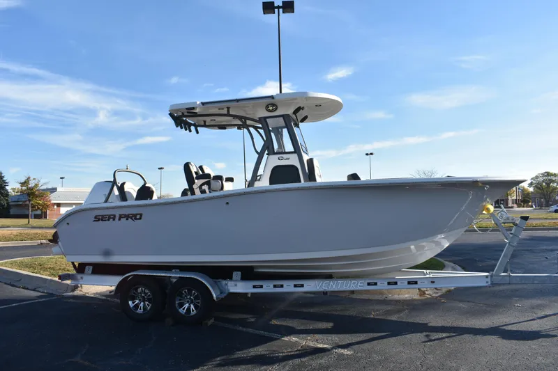 The Image of 2025 Sea Pro 245FLX Sandbar boat on trailer under clear blue sky. - 0