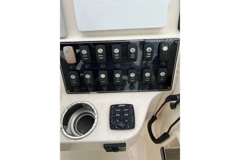 Slide: The Image of Control panel of 2019 Grady-White Freedom 235 boat with switches and cup holder. - 22