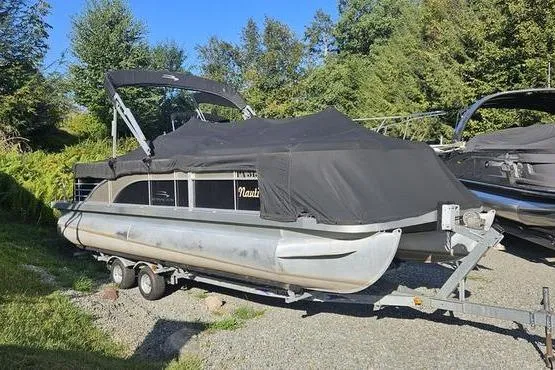 The Image of 2013 Bennington 2275 GCW pontoon boat covered on a trailer, surrounded by greenery. - 1