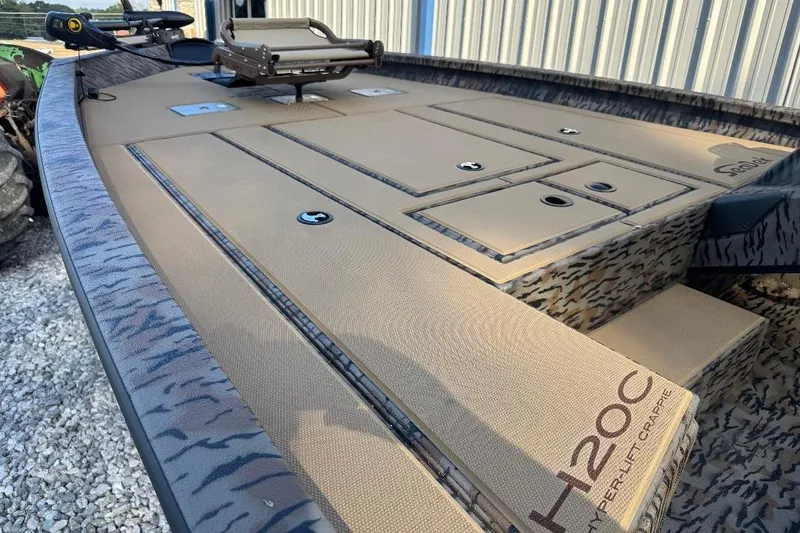 Slide: The Image of 2026 Xpress H20C Crappie boat deck with storage compartments and camouflage design. - 8