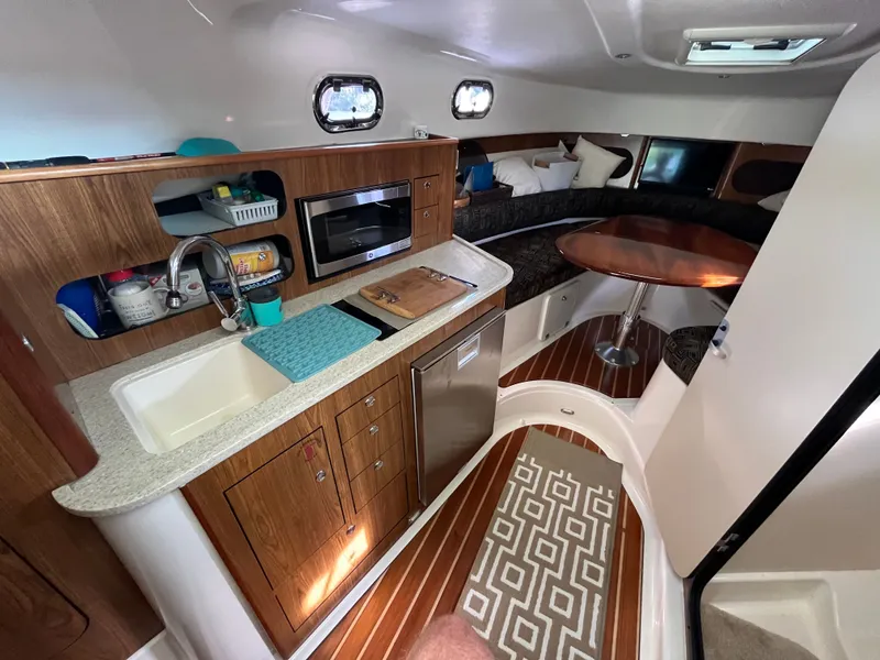 Slide: The Image of 2010 Pursuit OS 345 Offshore cabin with kitchenette, sink, microwave, and seating area. - 25