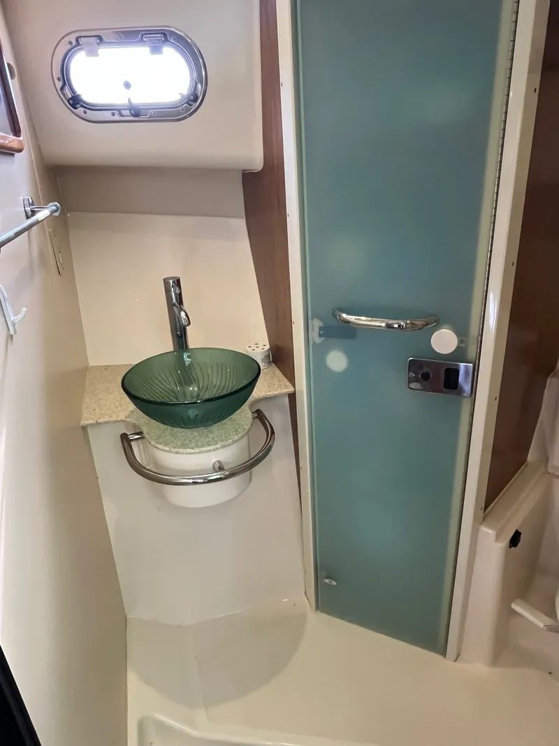 Slide: The Image of 2010 Pursuit OS 345 Offshore bathroom with glass sink and frosted door. - 27